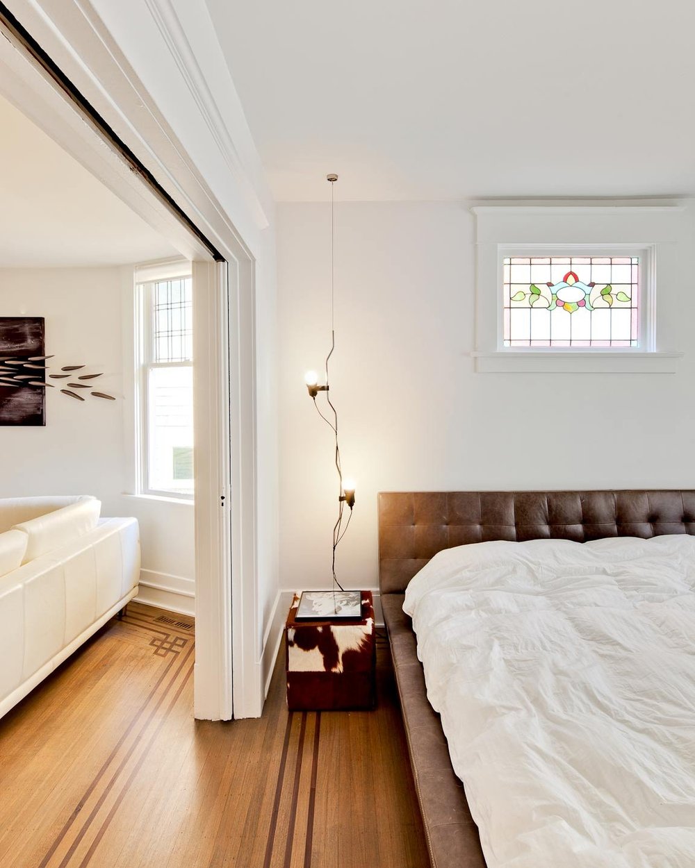 Kitsilano House — Bedroom with timber headboard and a small stained-glass window