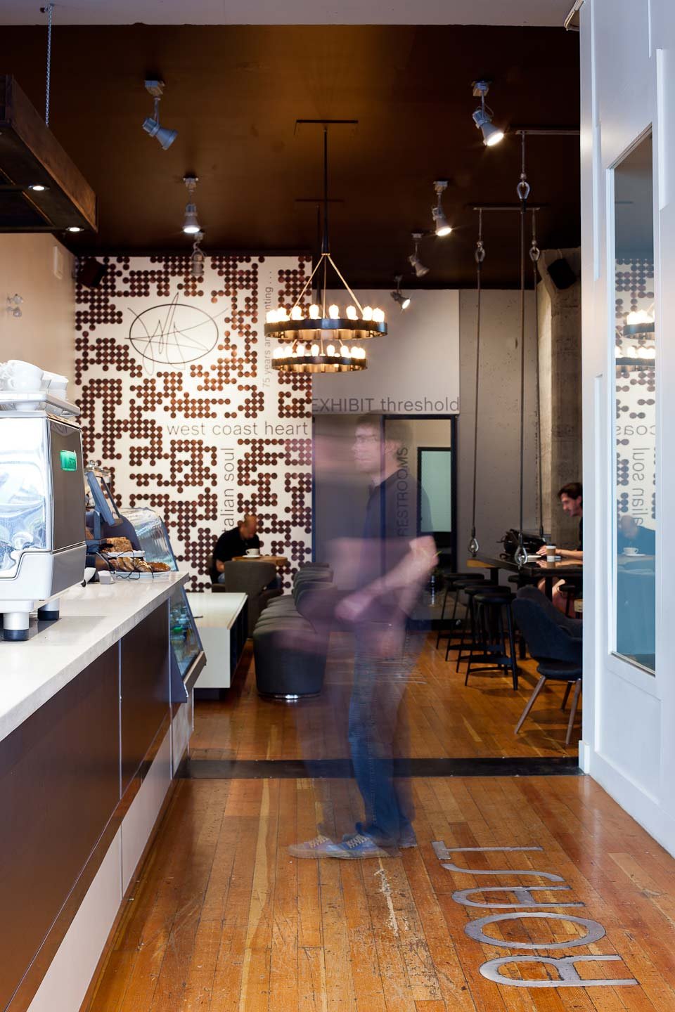 Espresso Lounge — Café counter and pendant lights with a person passing