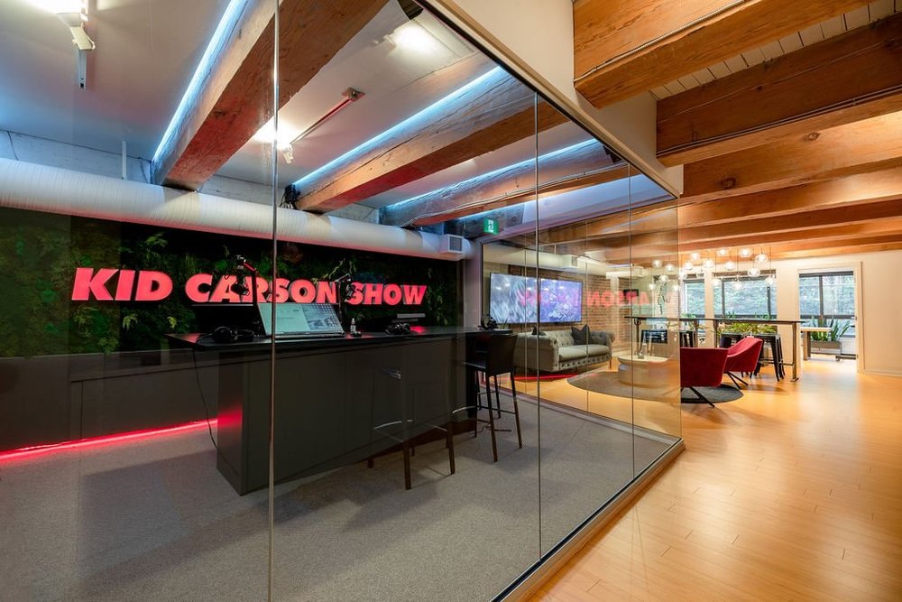 Podcast Studio — Glass-enclosed recording area opening onto a timber-floored lounge