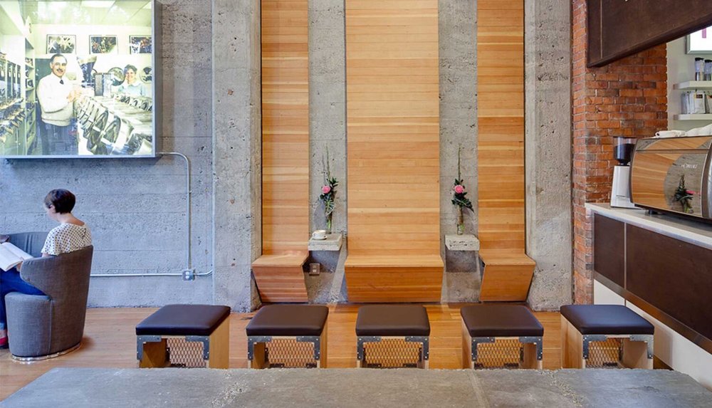 Espresso Lounge — Coffee lounge with timber wall panels, concrete columns and low stools