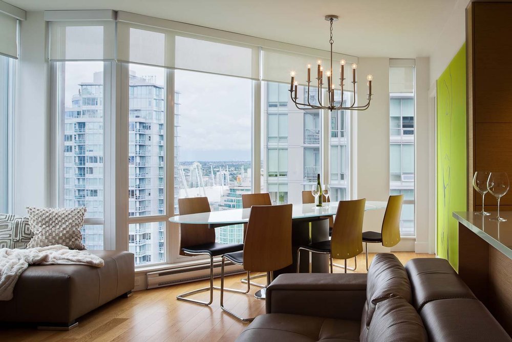 City Retreat — Apartment living and dining area with city windows and yellow chairs