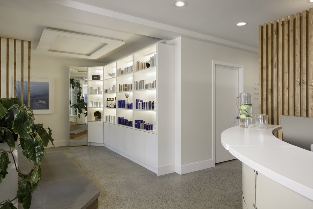 Skin Wellness Boutique — Boutique reception with curved counter, illuminated product shelves and timber slats