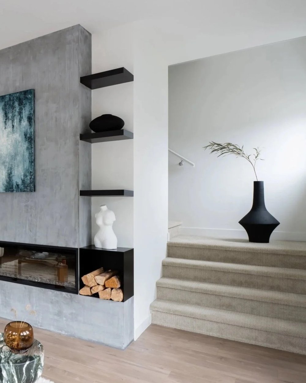 Britannia Beach House — Pale steps beside a concrete fireplace and black vase